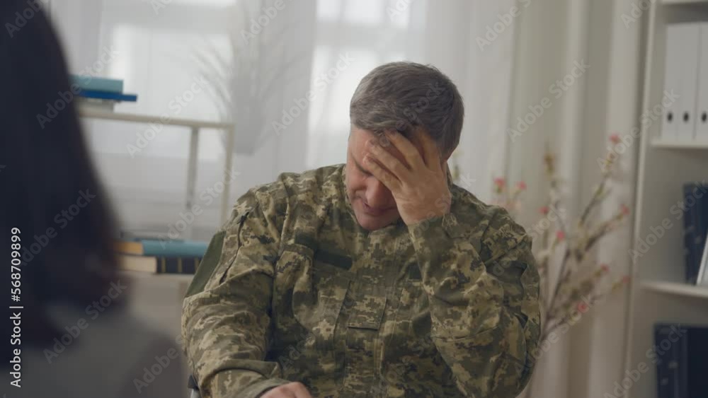 Middle-aged man in military uniform suffering headache at therapy session Middle-aged man in military uniform suffering headache at therapy session