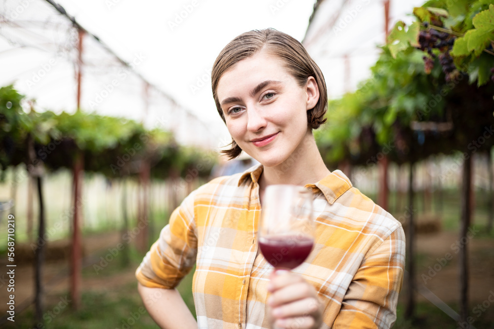 Happy charming woman standing and tasting in vineyard with glasses of vine red drinking, relaxing in summer day. Season of harvest Happy charming woman standing and tasting in vineyard with glasses of vine red drinking, relaxing in summer day. Season of harvest