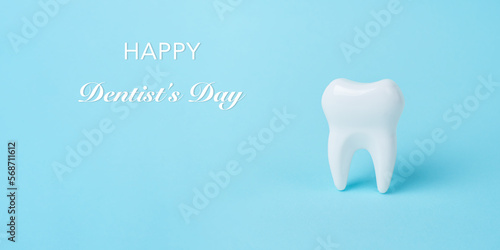 White tooth on blue background with copy space. Dental health concept. Dentist day, National False Teeth Day, Stomatology Day.