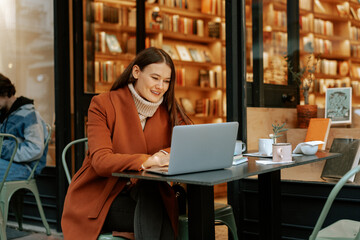Young woman working with her laptop sitting at the table in the street