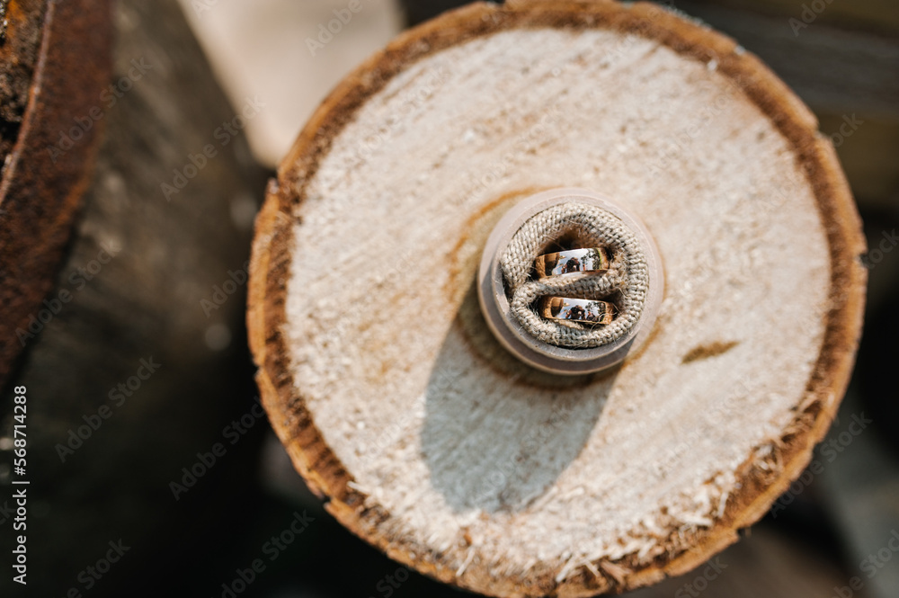 Wedding ring on wooden stump. Engagement. Wedding decor. Decorations against the background of wooden box. Top view. Wedding ring on wooden stump. Engagement. Wedding decor. Decorations against the background of wooden box. Top view.