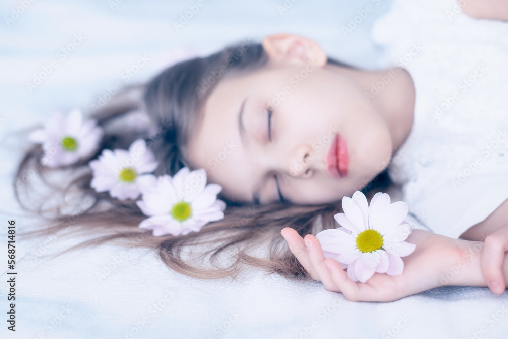 Close up portrait in pastel tones of a beautiful caucasian girl sleeping with daisy flowers in her long hair on white. Close up portrait in pastel tones of a beautiful caucasian girl sleeping with daisy flowers in her long hair on white.