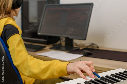 Fotografie Young teenager boy songwriter playing keyboard and writing song at home
