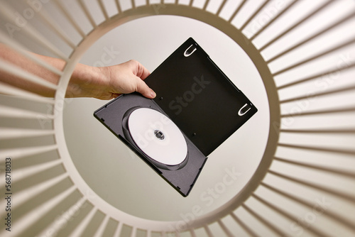 The DVD disc is thrown into the trash for disposal and recycling. View from below. The concept of disposal and processing of waste.