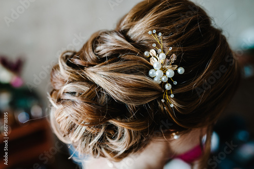 Luxury. Rich Stylish Brunette with Pearly Beads. Elegant Style. Close-up shot of female hair-do made as a strand of hair fixed with a gold hair clip.