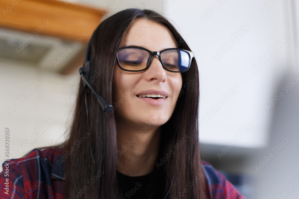 Portrait of cheerful young woman wearing headset with microphone. Friendly online support operator talks to client on a phone call Portrait of cheerful young woman wearing headset with microphone. Friendly online support operator talks to client on a phone call