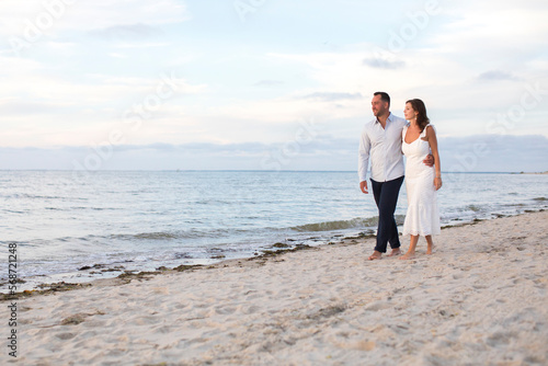 romantic couple walking arm in arm at beach