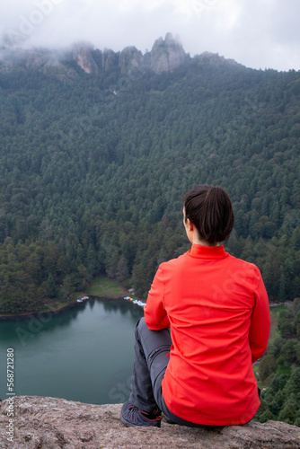 Female mexican hiker sitted on edge of cliff, admiring the view