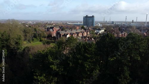 Aerial view over park trees to industrial townscape with blue skyscraper downtown, Merseyside, England photo