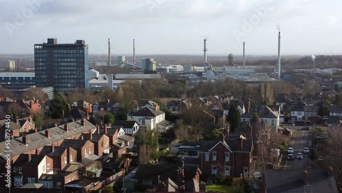 Aerial view over park trees to industrial townscape with blue skyscraper, Merseyside, England, Zoom in shot photo