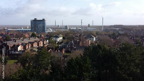 Aerial view over park trees to industrial townscape housing with Pilkingtons blue skyscraper, Merseyside, England photo