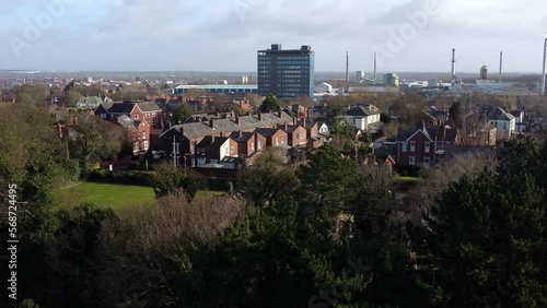 Aerial view over park trees to suburban industrial townscape with blue skyscraper, Merseyside, England photo