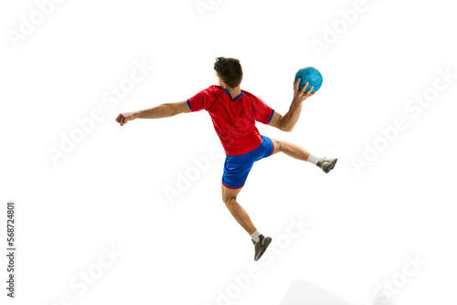 Back view. Throwing ball in a jump. Young man, professional handball player in red uniform playing, training isolated over white studio background. Concept of sport, action, motion, sportive lifestyle