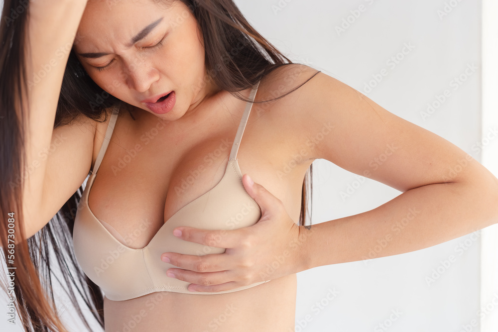 Female breast pain hand touching her breast screening by self. woman checks lump in her breast with her fist to investigate for breast cancer herself. Have chest pain. Female breast pain hand touching her breast screening by self. woman checks lump in her breast with her fist to investigate for breast cancer herself. Have chest pain.
