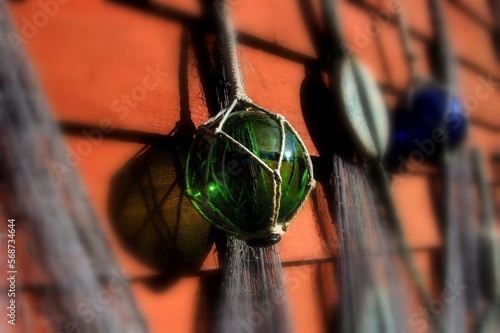 Old fashioned fishing net with colorful glass balls and bobbers hanging on a red wall