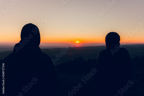 Couple of two boys watching the horizon and the sunset backlit together