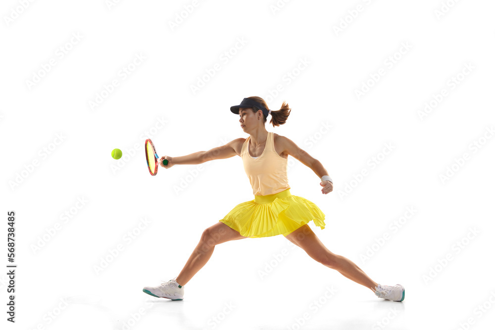 Studio shot of professional young female tennis player in sports uniform training with tennis racket isoltaed over white background. Concept of skills, sport, fashion, ad
