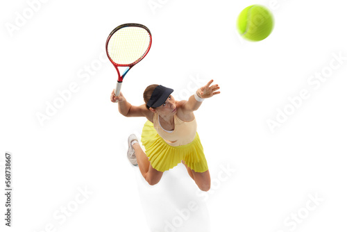 Aerial view of female professional tennis player doing powerful serving in tennis isolated over white background. Sport, fashion, power, energy, ad concept