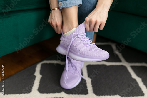 Slika na platnu Unrecognizable cropped female hands trying on sportive pink sneakers, trying on