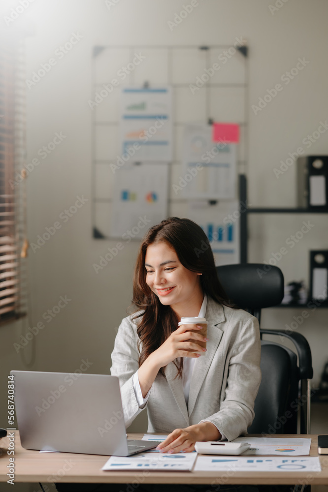 Young beautiful woman typing on tablet and laptop while sitting at the working wooden table office Young beautiful woman typing on tablet and laptop while sitting at the working wooden table office