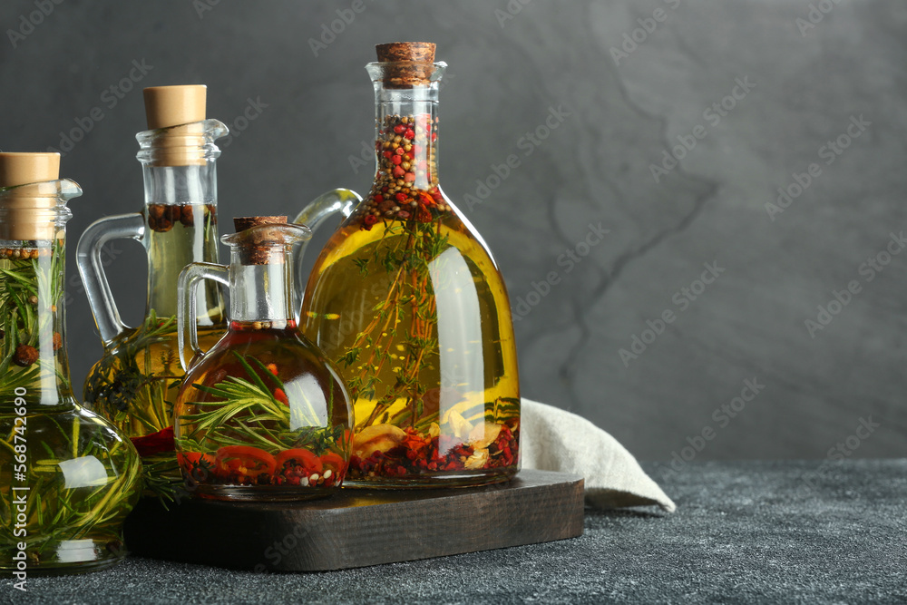 Cooking oil with different spices and herbs in jugs on light grey table. Space for text