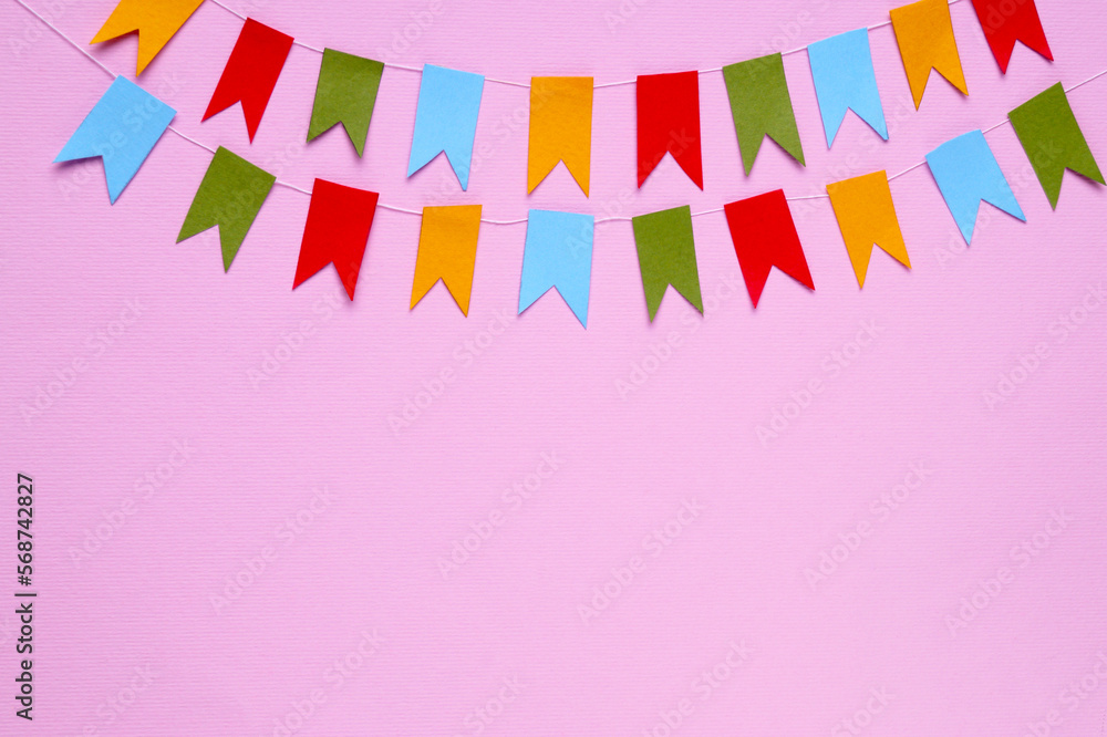 Obraz premium Colorful bunting flags on pink background, flat lay. Space for text