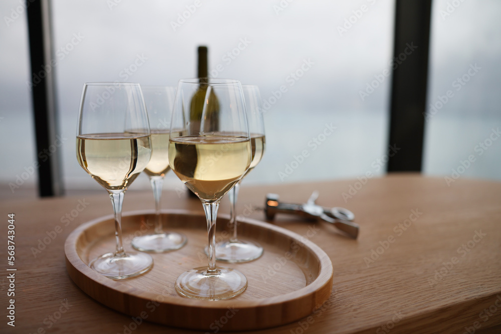 White wine in glasses standing on wooden tray closeup