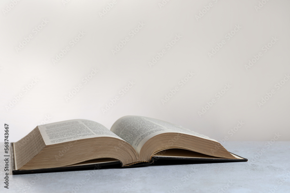 Open hardcover Bible on light grey table, space for text. Religious book Open hardcover Bible on light grey table, space for text. Religious book