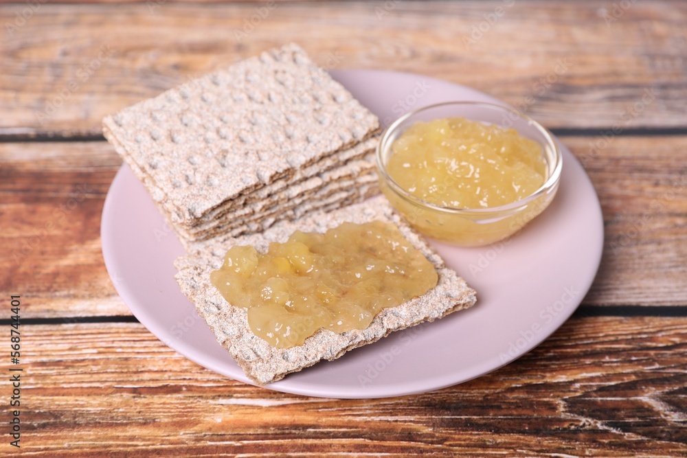 Tasty crispbreads with jam on wooden table, closeup Tasty crispbreads with jam on wooden table, closeup