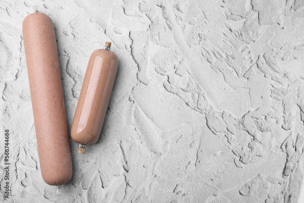 Delicious liver sausages on white textured table, flat lay. Space for text Delicious liver sausages on white textured table, flat lay. Space for text