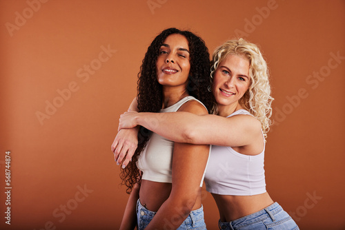 Diverse young female friends smiling against an orange background
