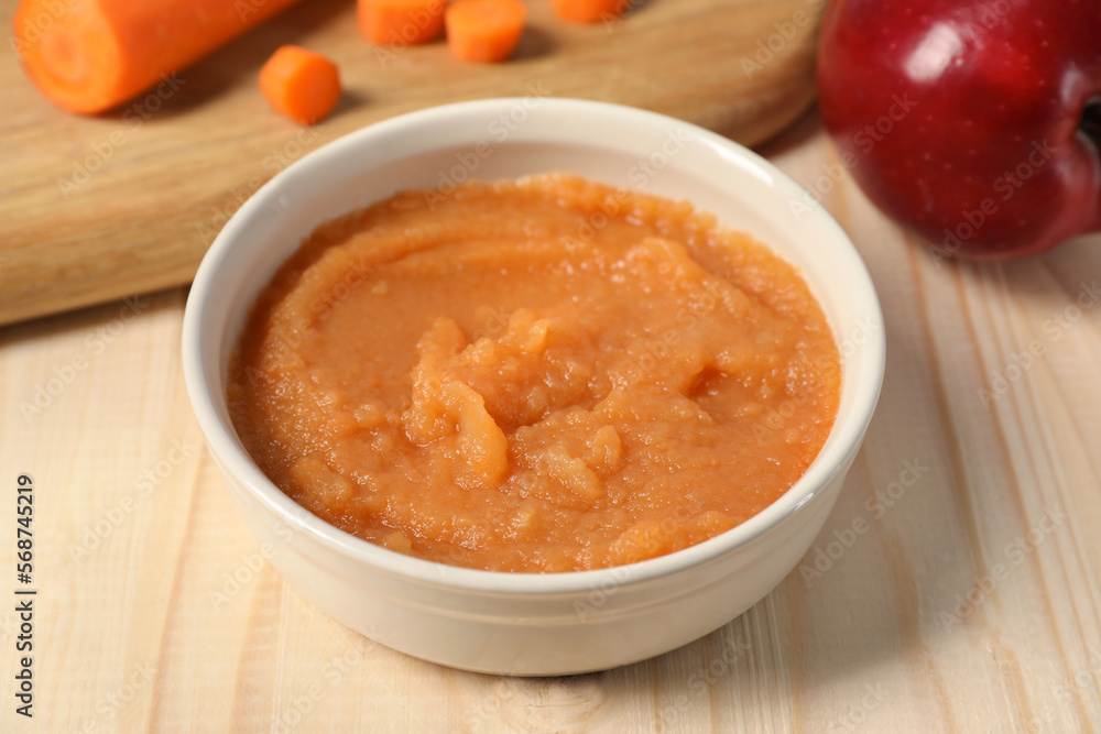 Healthy baby food. Bowl with delicious carrot puree on wooden table, closeup Healthy baby food. Bowl with delicious carrot puree on wooden table, closeup