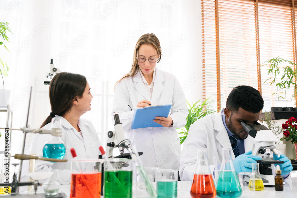 The diversity of scientists reports experimentation results to their colleagues in the research laboratory. Group of chemistry students working in the laboratory. The diversity of scientists reports experimentation results to their colleagues in the research laboratory. Group of chemistry students working in the laboratory.