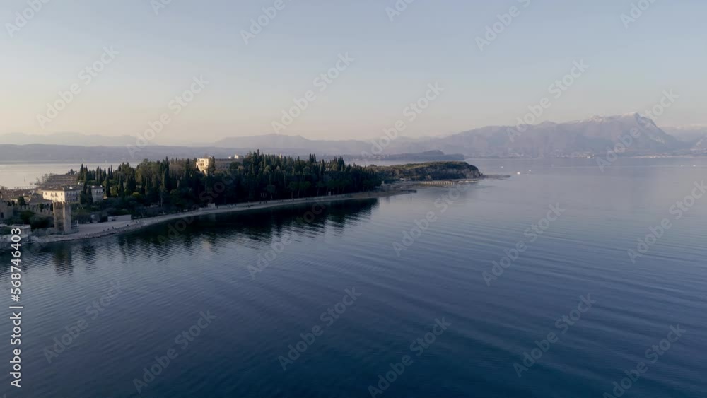 Aerial view Sirmione mediterranean historical sightseeing town in italy, lake garda. Beautiful castle on water, wide angle of peninsula with historical town, sunset flight, summer tourism destination Aerial view Sirmione mediterranean historical sightseeing town in italy, lake garda. Beautiful castle on water, wide angle of peninsula with historical town, sunset flight, summer tourism destination