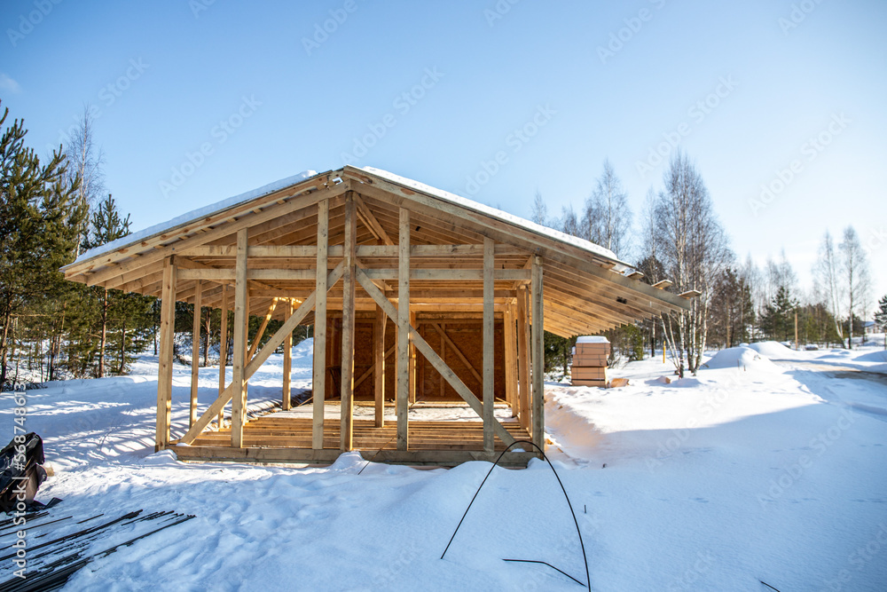 Wood frame house under construction, bare frame and walls with pile foundation, winter season Wood frame house under construction, bare frame and walls with pile foundation, winter season