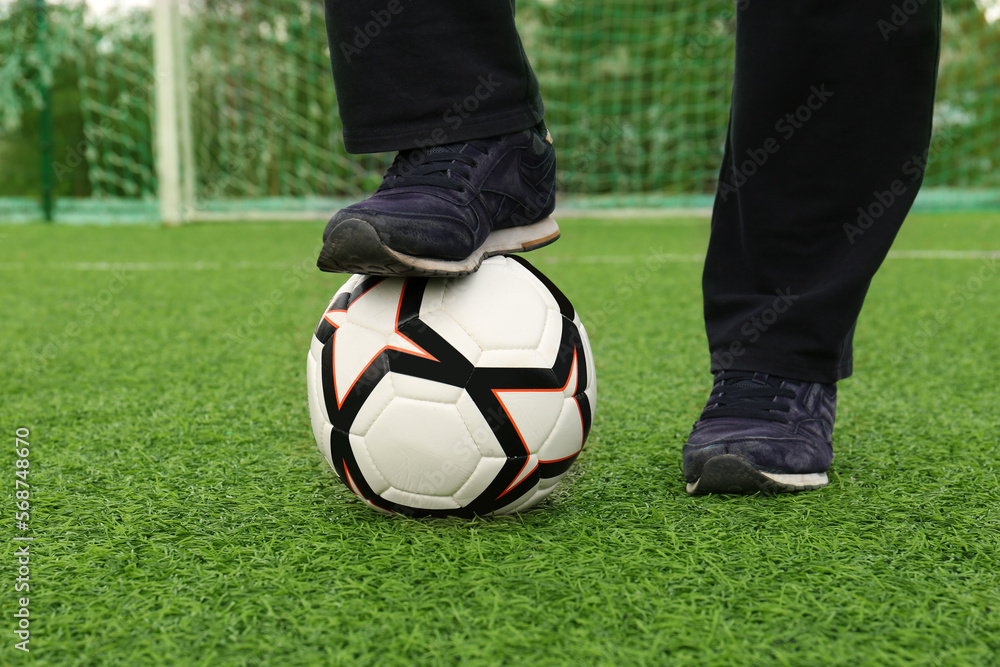 Obraz premium Man with soccer ball on green grass at stadium, closeup