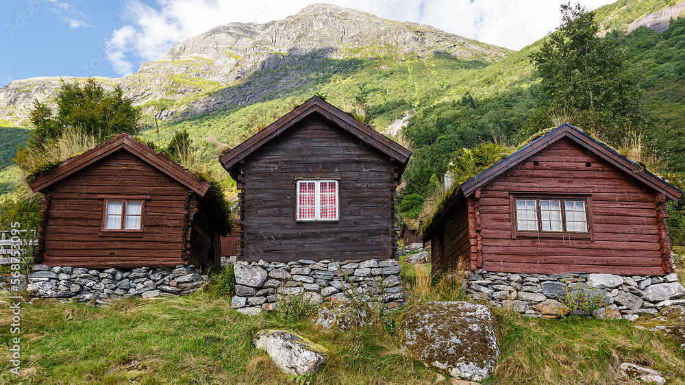 Drei Holzhütten stehen an einem Berg