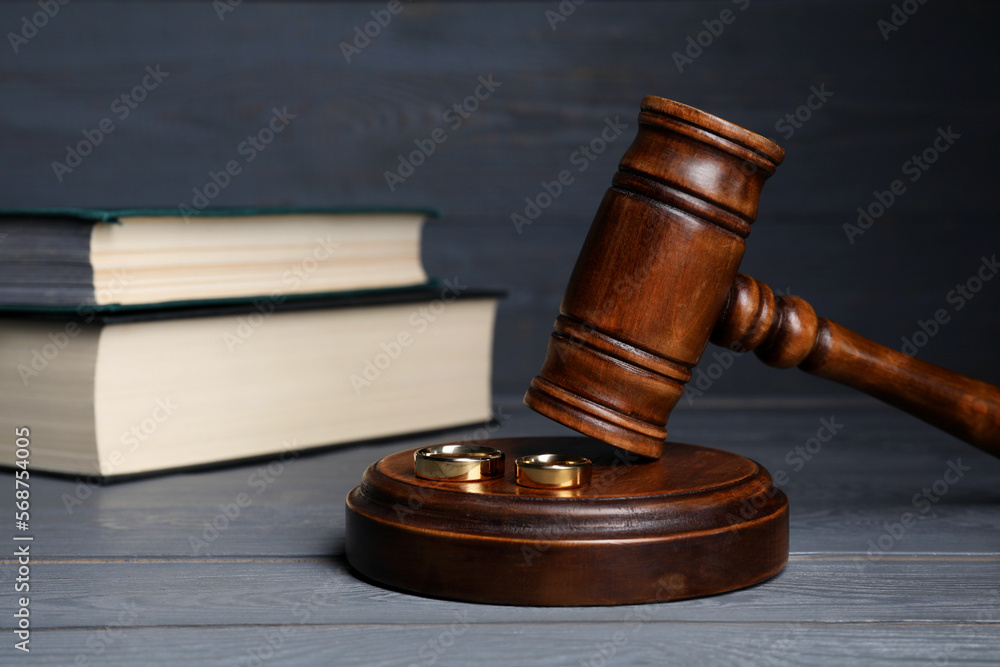 Divorce concept. Gavel and wedding rings on grey wooden table, space for text Divorce concept. Gavel and wedding rings on grey wooden table, space for text