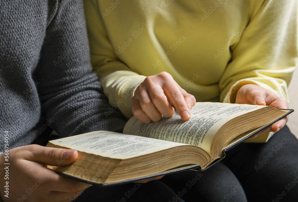 Couple sitting and reading holy Bible, closeup Couple sitting and reading holy Bible, closeup