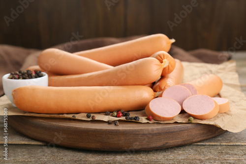 Tasty sausages and peppercorns on wooden table, closeup. Meat product