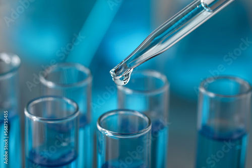 Dripping liquid from pipette into test tube in laboratory, closeup