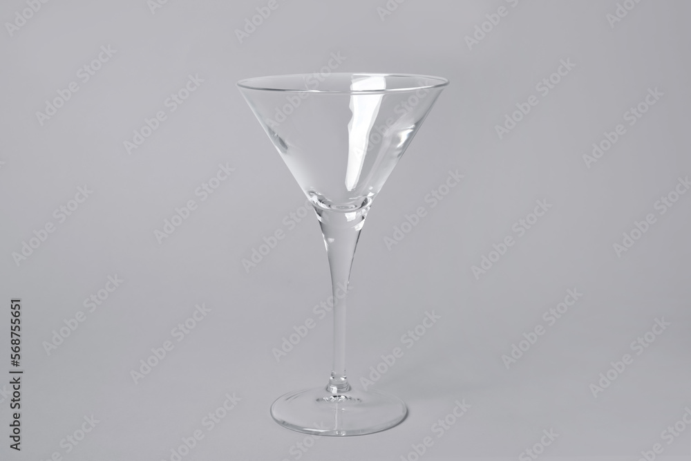 Empty clean martini glass on grey background Empty clean martini glass on grey background