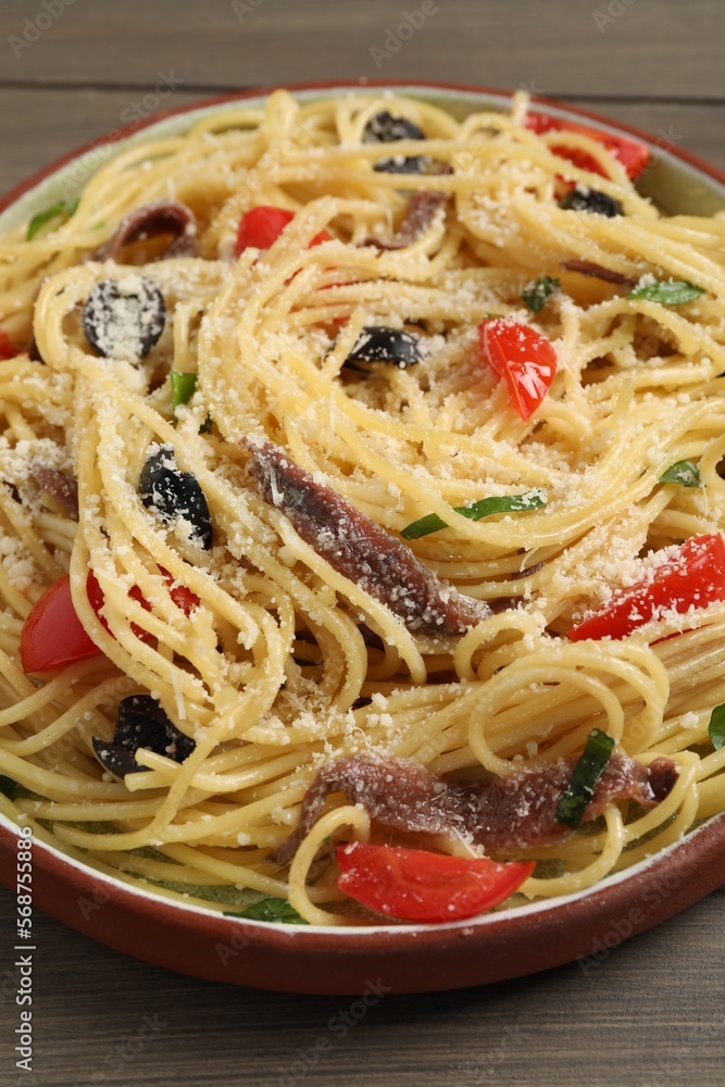 Plate of delicious pasta with anchovies, tomatoes and parmesan cheese on wooden table, closeup Plate of delicious pasta with anchovies, tomatoes and parmesan cheese on wooden table, closeup
