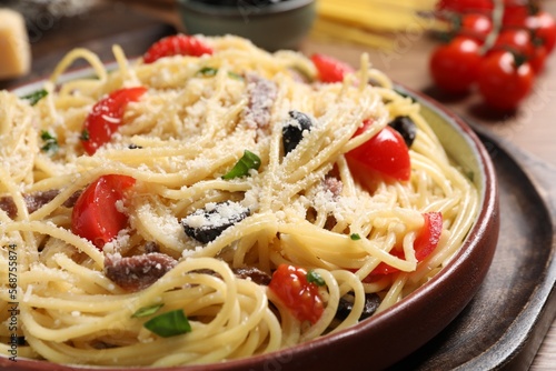 Delicious pasta with anchovies, tomatoes and parmesan cheese on table, closeup