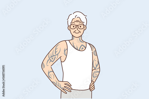 Elderly man with tattoos on arms and body stands with hands on belt proud good health in old age