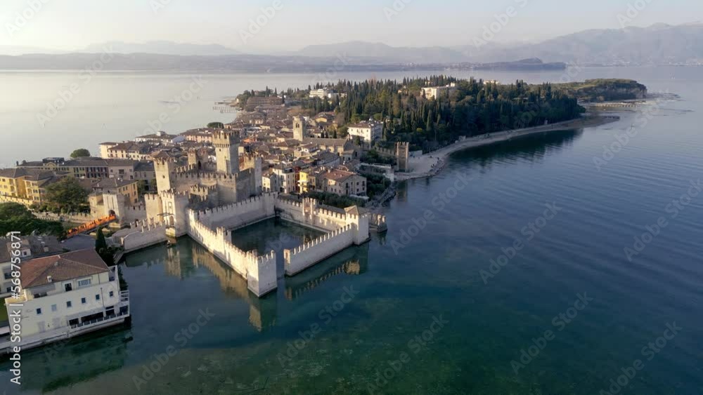 Aerial view Sirmione mediterranean historical sightseeing town in italy, lake garda. Beautiful castle on water, wide angle of peninsula with historical town, sunset flight, summer tourism destination Aerial view Sirmione mediterranean historical sightseeing town in italy, lake garda. Beautiful castle on water, wide angle of peninsula with historical town, sunset flight, summer tourism destination
