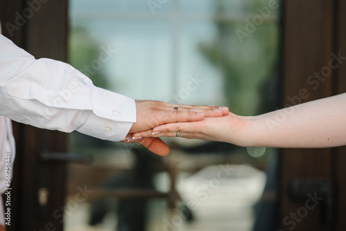 The Bride and groom holding hands. Rings. Engagement. Hands are newlyweds with wedding rings. Men's ring with ornament. Women's ring with stones.