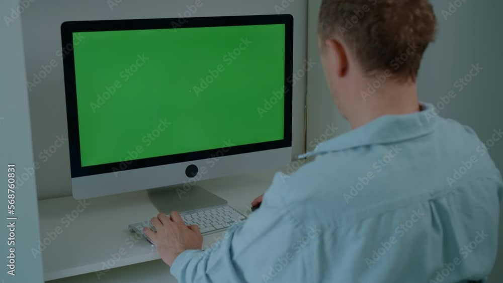 manager works in the office rear view man sitting at the workplace typing on white keyboard using computer mouse display with green screen manager works in the office rear view man sitting at the workplace typing on white keyboard using computer mouse display with green screen