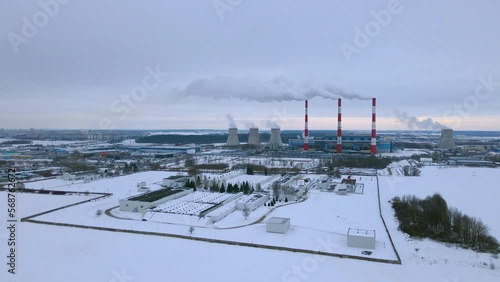 Thermal power plant CHP winter sunny day aerial view. Smoke from chimneys against the background of a gloomy sky. 4K view.