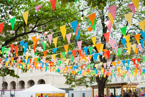 Easter market with colorful flags bunting banner and lights decoration. Festive happy birthday celebration background. © Dina